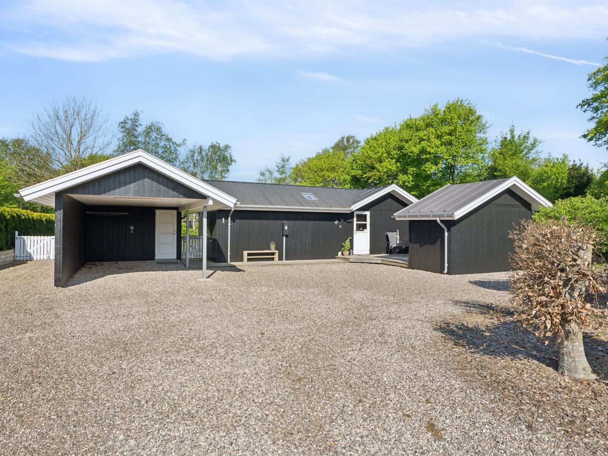 A modern building with a gravel driveway and a covered carport.