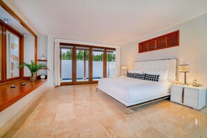 A bedroom with a large bed, a nightstand, a mirror, and a sliding glass door leading to a balcony. - Srvittinivillas Agp36 / Spacius / Confortable Luxury Villa/ Family/ Team/ Cdc (La Romana)