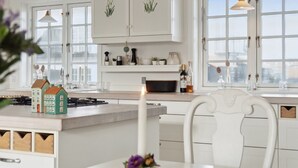 Een moderne keuken met witte kasten, een centraal eiland en uitzicht door grote ramen.