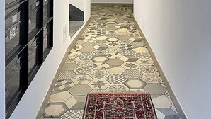 A narrow hallway with patterned hexagonal tiles, a black metal filing cabinet, and a red rug at the end. - Studio 505 - Sion Old City - Swiss Alps (Sion)