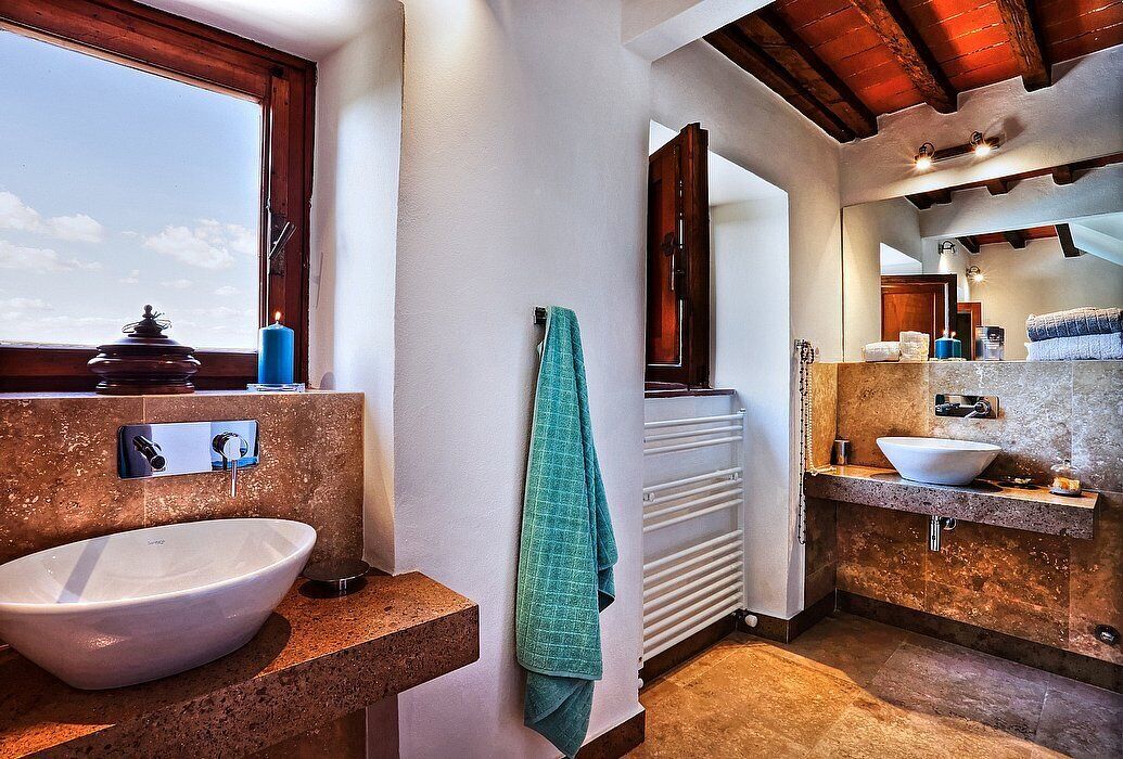 A modern bathroom with a large window, a white sink, a towel rack, and a mirror.