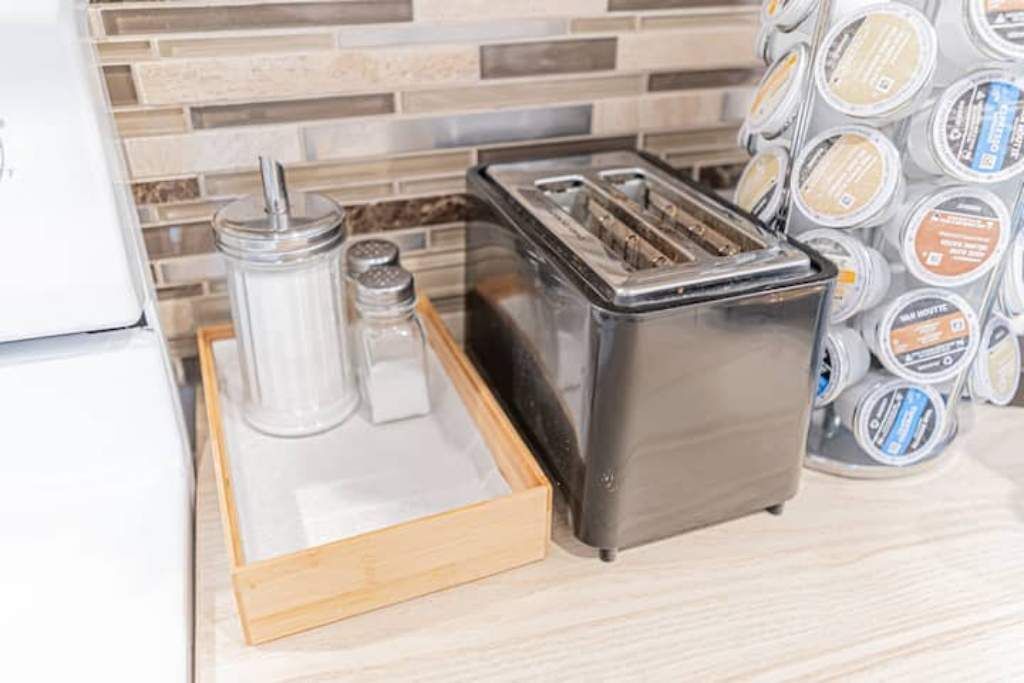 A kitchen counter with a toaster, a salt shaker, and a pepper shaker on a wooden tray.
