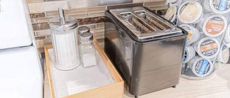 A kitchen counter with a toaster, a salt shaker, and a pepper shaker on a wooden tray.