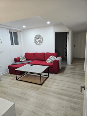 A living room with a red sofa, a coffee table, and a wall art piece.