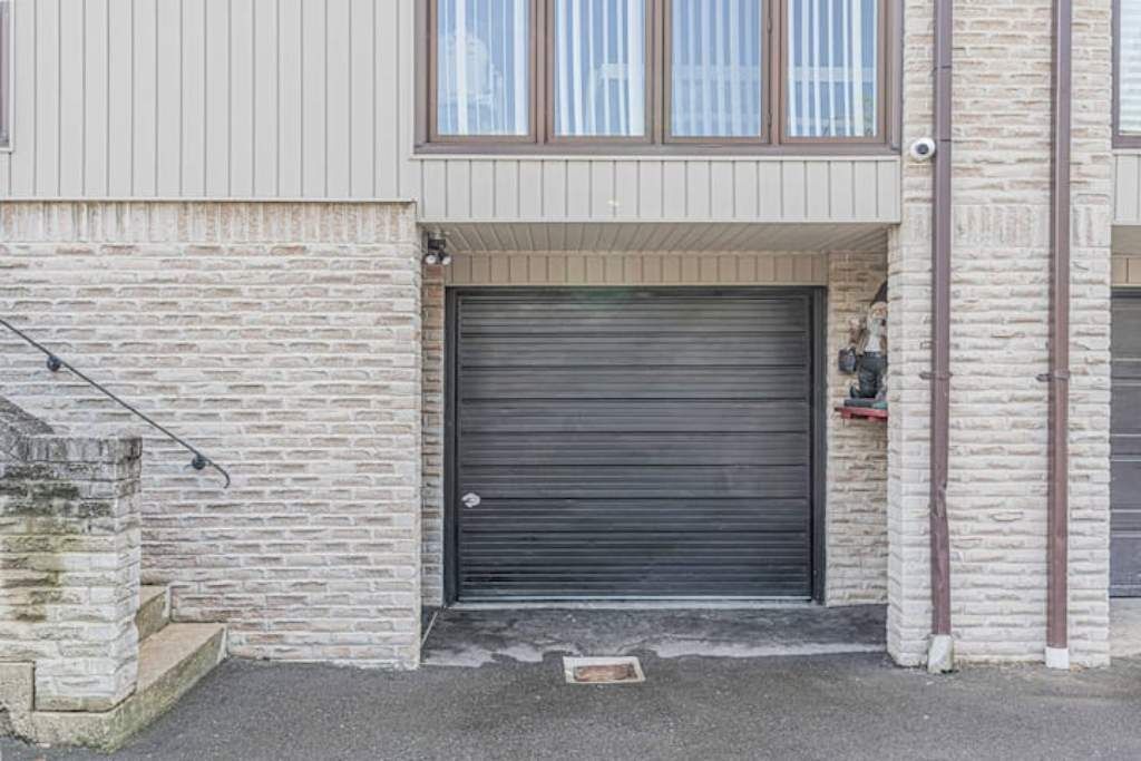 A building with a stone facade, a closed roller shutter door, and a small step leading up to the entrance.
