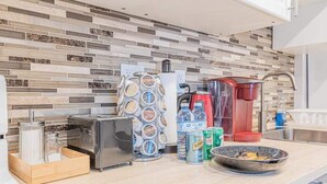A modern kitchen with a tiled backsplash, a coffee machine, a blender, a toaster, and a bowl of fruit on the counter. - Mississauga 2BDR Lower Unit Parking Self-check in (Mississauga)