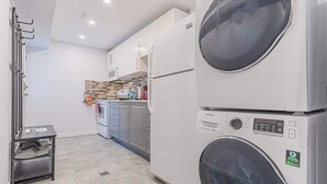 A compact kitchen with modern appliances, including a stacked washer and dryer, and a small metal rack for hanging items. - Mississauga 2BDR Lower Unit Parking Self-check in (Mississauga)