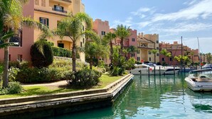 A marina with boats docked, surrounded by buildings with balconies and lush greenery. - Experience sophistication in this contemporary four-bedroom frontline golf townhouse (San Roque)