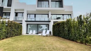 A modern two-story house with a well-maintained lawn and white outdoor furniture. - Experience sophistication in this contemporary four-bedroom frontline golf townhouse (San Roque)