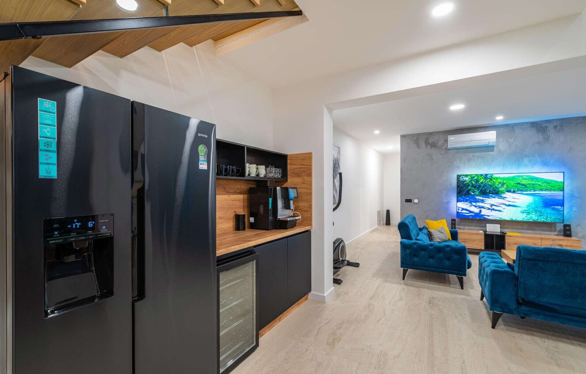 A modern kitchen with a built-in coffee machine and a black refrigerator.