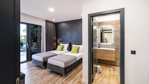 Une chambre d’hôtel moderne avec deux lits, une grande fenêtre et une salle de bain équipée d’un miroir et d’un lavabo.