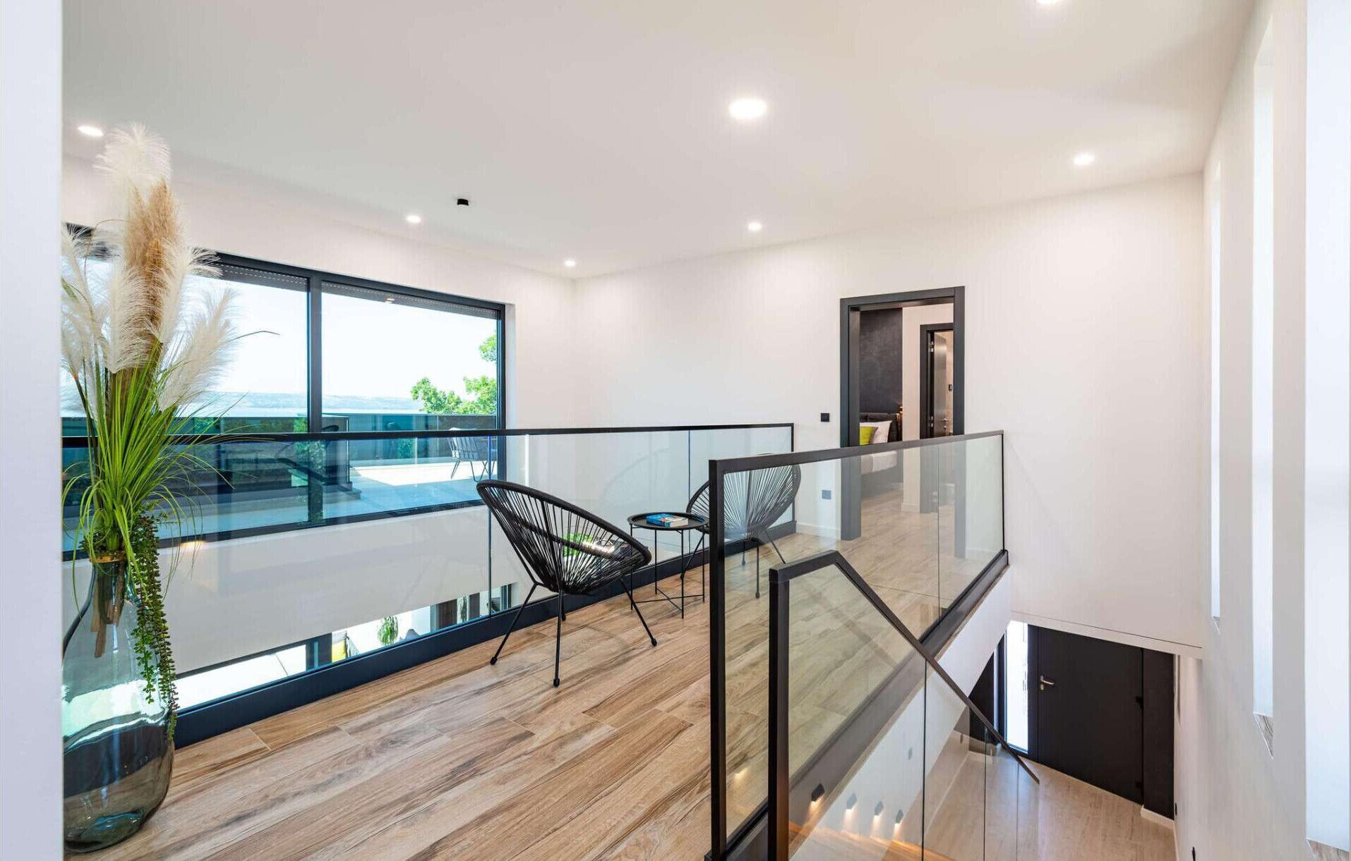 Ein modernes Interieur mit Glastrennwand, Holzboden und Blick ins Freie.
