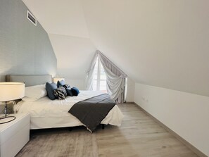 Une chambre à coucher avec un lit, une table de chevet, une lampe et une fenêtre avec des rideaux.
