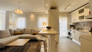 A modern apartment with a living area, kitchenette, and a dining area. - 3010 Spacious Luxury Family Apartment in Marbella's Heart (Marbella)