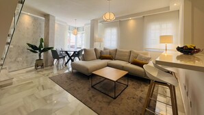 A modern living room with a sectional sofa, a coffee table, and a dining area with chairs and a table. - 3010 Spacious Luxury Family Apartment in Marbella's Heart (Marbella)