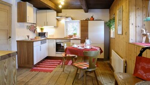 Een gezellige keuken met houten kasten, een eettafel met stoelen en een rood vloerkleed.