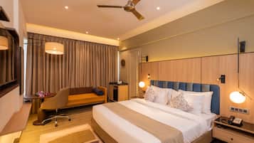 Una habitación de hotel moderna con una cama grande, un escritorio, una silla y un ventilador de techo.