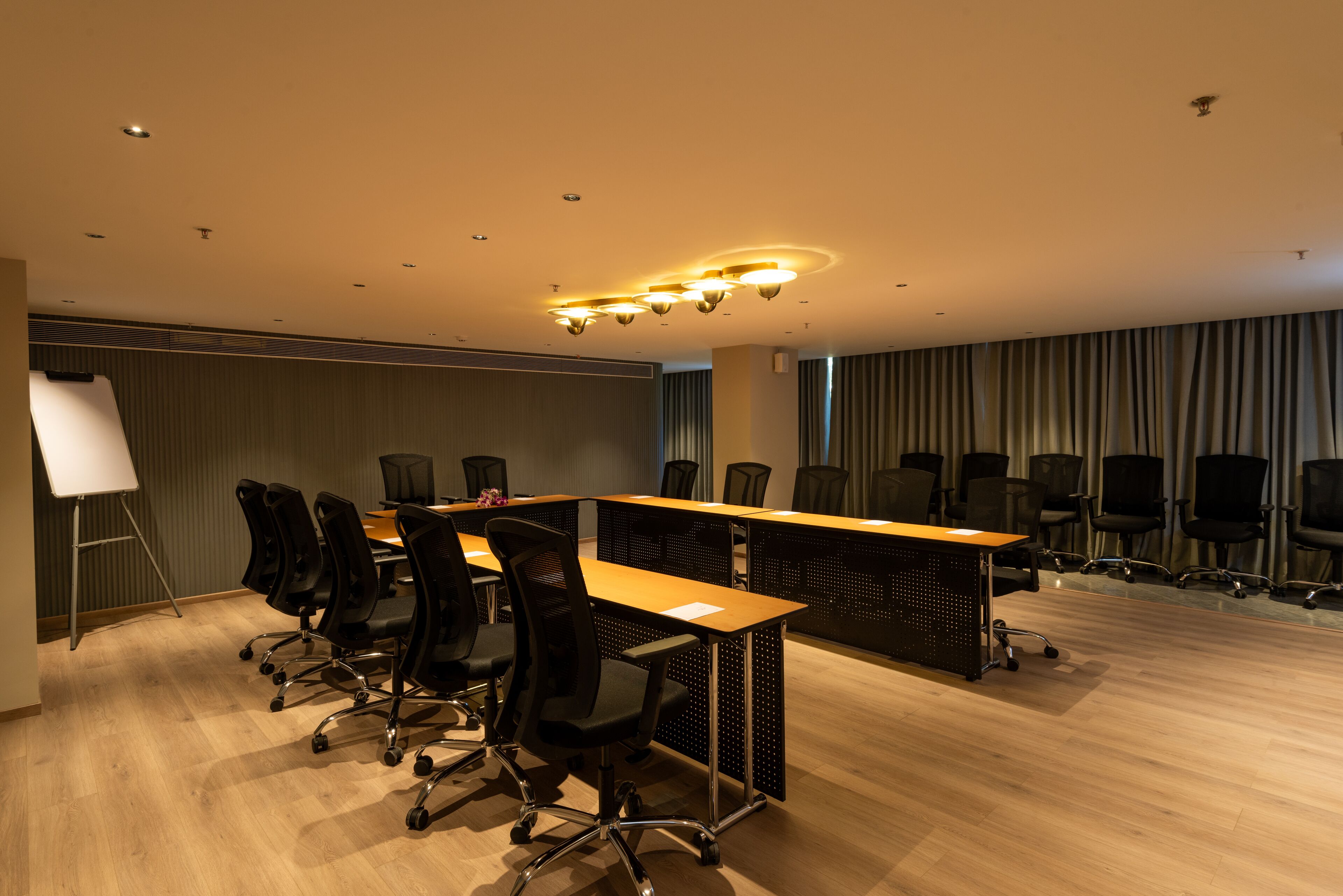 Un salón de conferencias con una larga mesa, varias sillas, una pizarra y una pantalla para proyector.