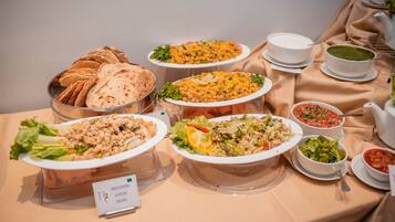 Una mesa de buffet con diversos platos, incluyendo pasta, ensaladas y pan.
