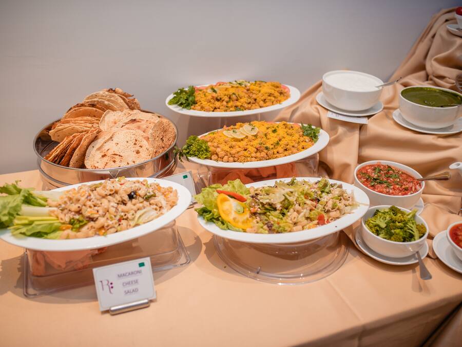 Una mesa de buffet con diversos platos, incluyendo pasta, ensaladas y pan.