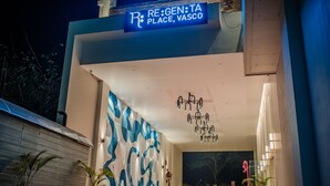 L’entrée d’un hôtel au design moderne, ornée d’une grande fresque abstraite et d’une enseigne sur laquelle on peut lire : « RE:GEN:TA PLACE, VASCO ».
