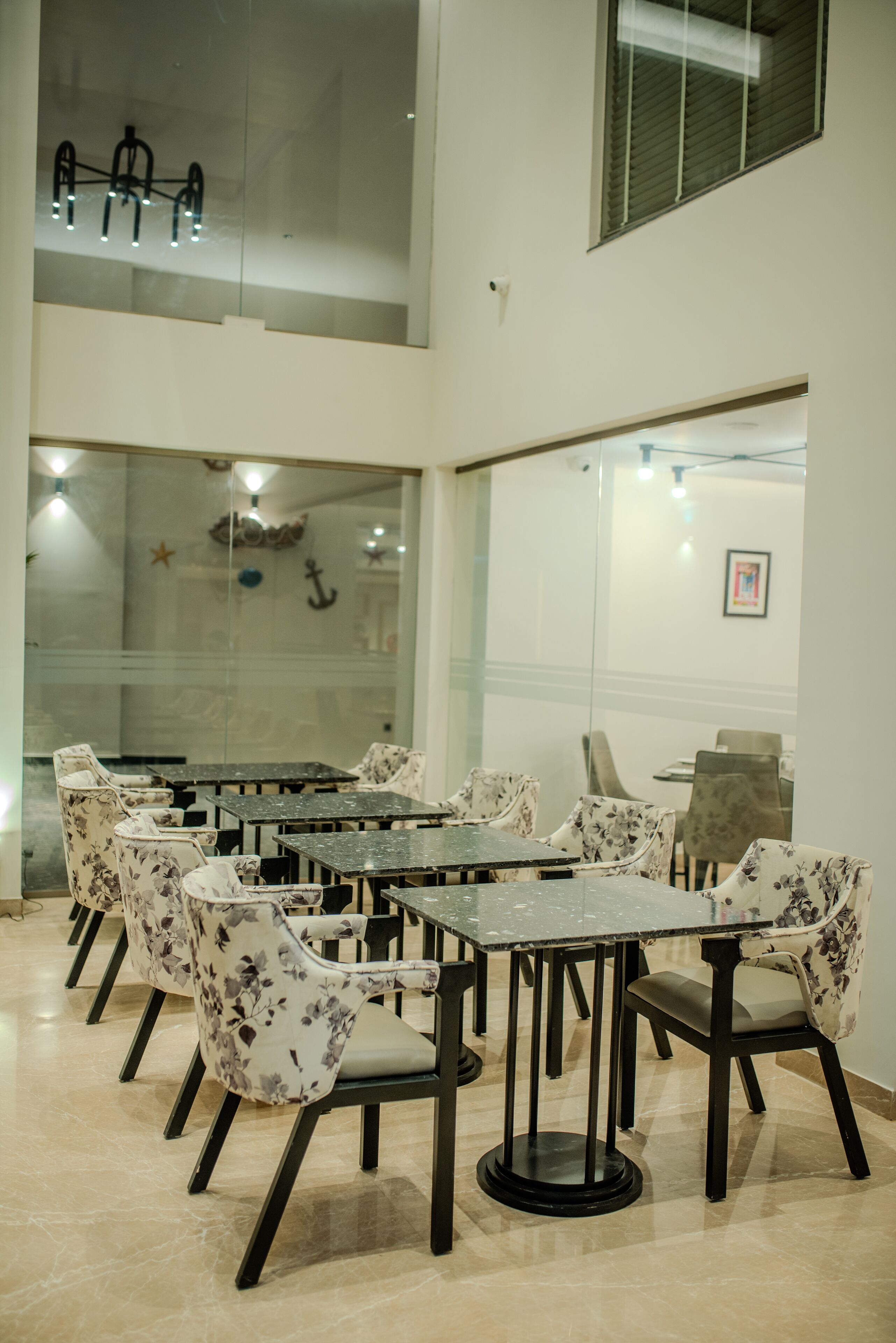 Un salón de conferencias con paredes de vidrio, varias mesas y sillas con estampado floral.
