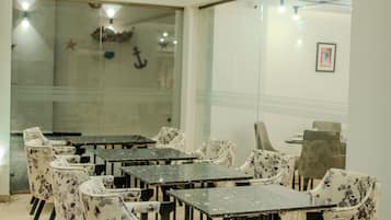 Un salón de conferencias con paredes de vidrio, varias mesas y sillas con estampado floral.
