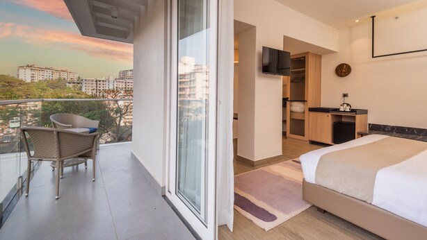 Une chambre d’hôtel moderne dotée d’un balcon, d’un lit, d’une télévision et d’une salle de bain.