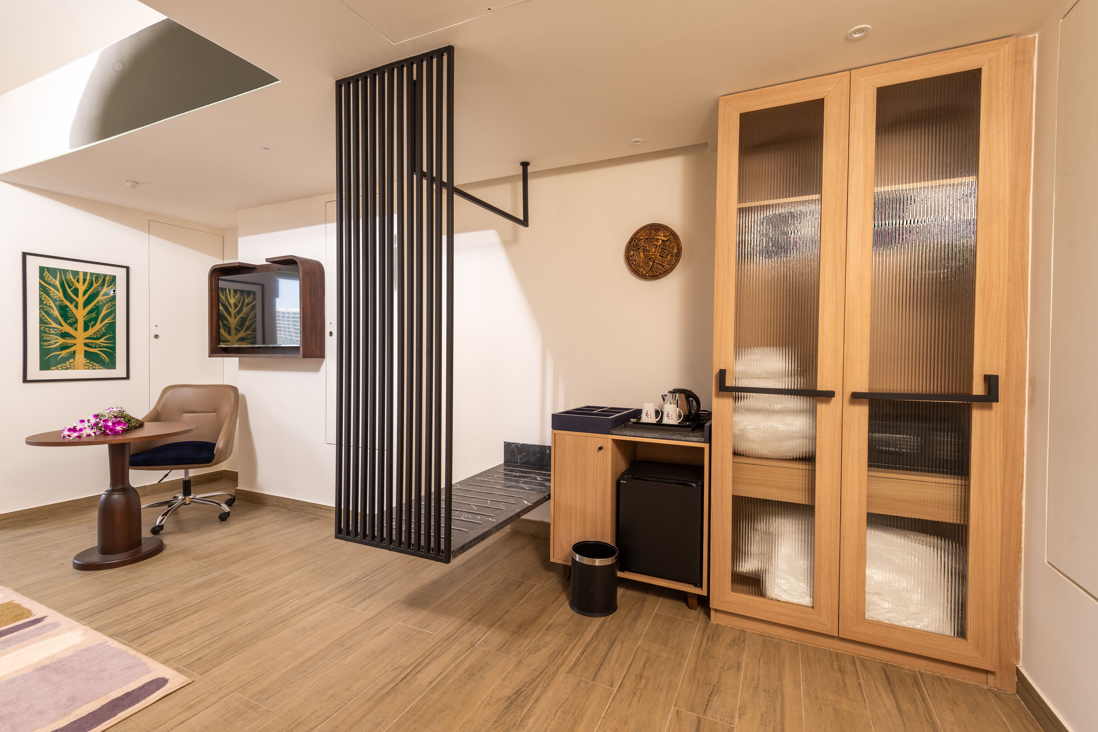 A modern room with a desk, chair, and a large wooden cabinet with glass doors.
