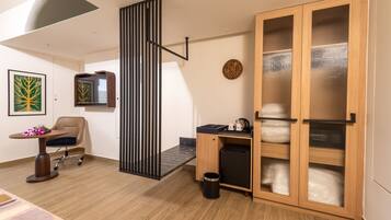 Una habitación moderna con escritorio, silla y un mueble grande de madera con puertas de vidrio.