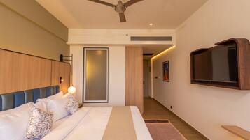 Un dormitorio moderno con una cama, un ventilador de techo, un televisor montado en la pared y un armario de madera.