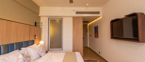 A modern bedroom with a bed, a ceiling fan, a TV mounted on the wall, and a wooden wardrobe.