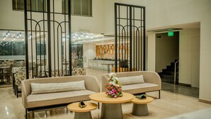 Un hall d'entrée moderne avec un canapé, deux tables rondes et un arbre de Noël décoratif.