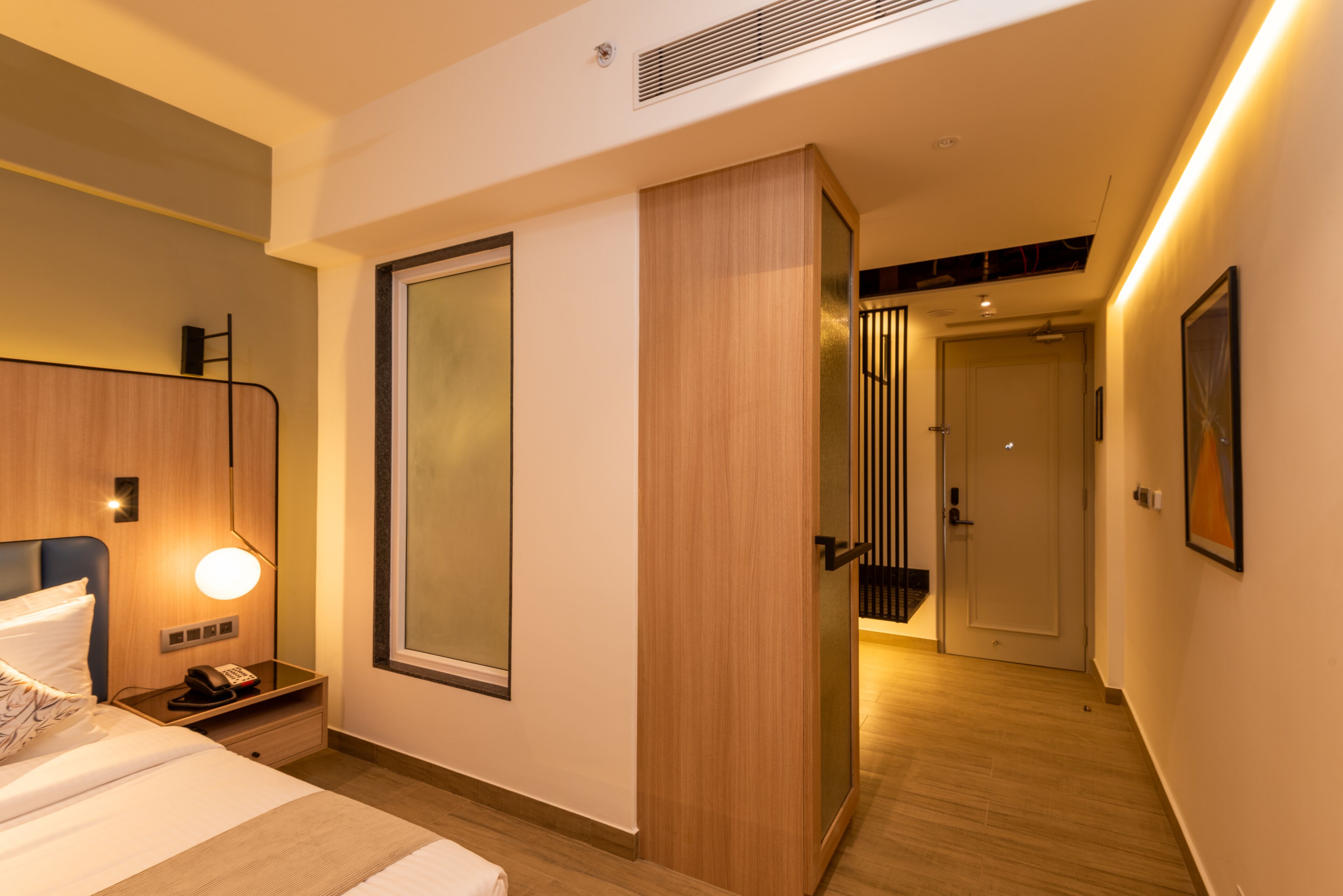 Een moderne hotelkamer met een bed, nachtkastje en een grote spiegel.