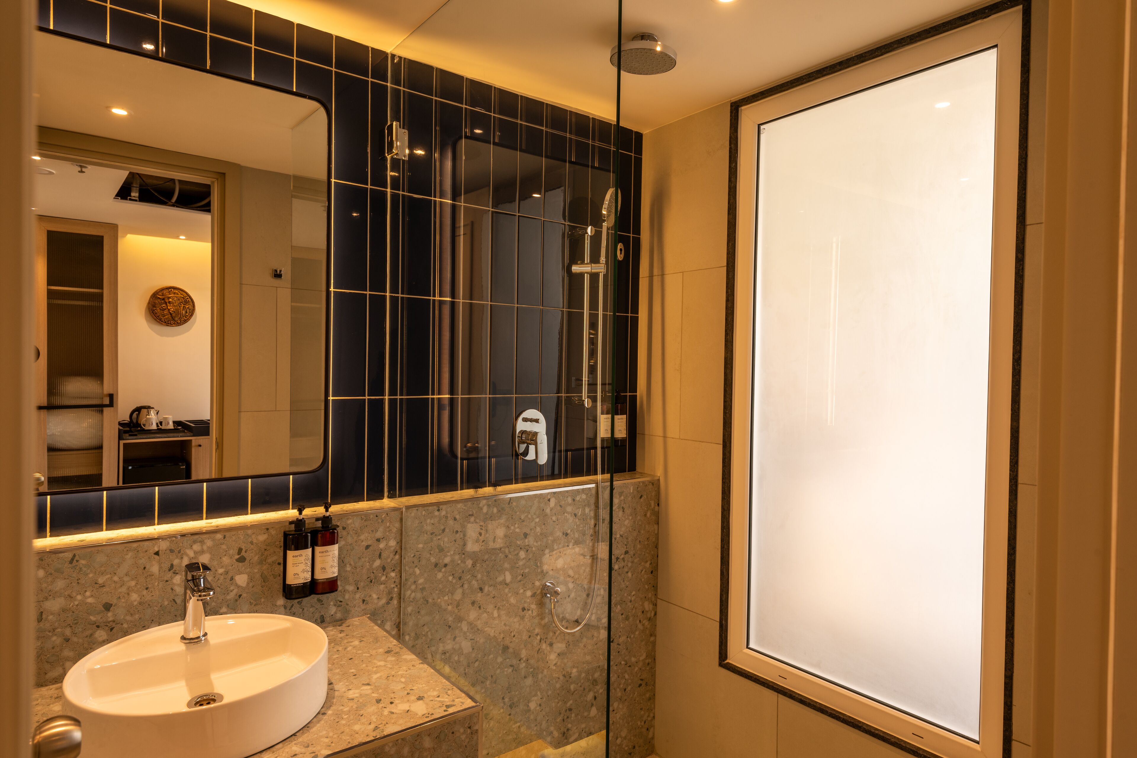 A modern bathroom with a round sink, a large mirror, and a glass-enclosed shower.
