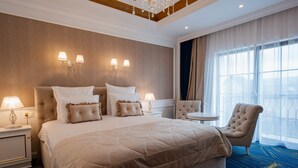 Una habitación de hotel con una cama grande, dos lámparas de noche, una mesa redonda y una silla.