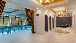 Un amplio espacio interior con un gran ventanal, piscina y zona de descanso con una tumbona.