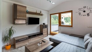 A modern bedroom with a bed, a TV, a wooden cabinet, and a window with a view. - Apartment Neukirchen near Ski Slopes (Neukirchen am Großvenediger)