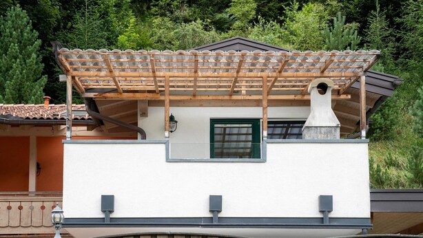 A modern building with a wooden pergola, a chimney, and a window. - Apartment Neukirchen near Ski Slopes (Neukirchen am Großvenediger)