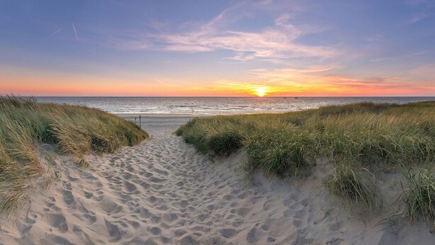 A beach path leading to the ocean with a sunset in the background. - Family Getaway in Texel (De Koog)