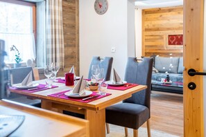 A dining area with a wooden table set for four, including plates, glasses, and cutlery.