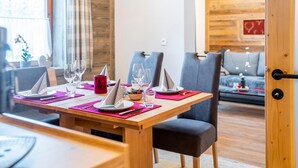A dining area with a wooden table set for four, including plates, glasses, and cutlery. There are two chairs, a red mug, and a clock on the wall. - Chalet in Neukirchen near Ski Arena Wildkogel (Neukirchen am Großvenediger)