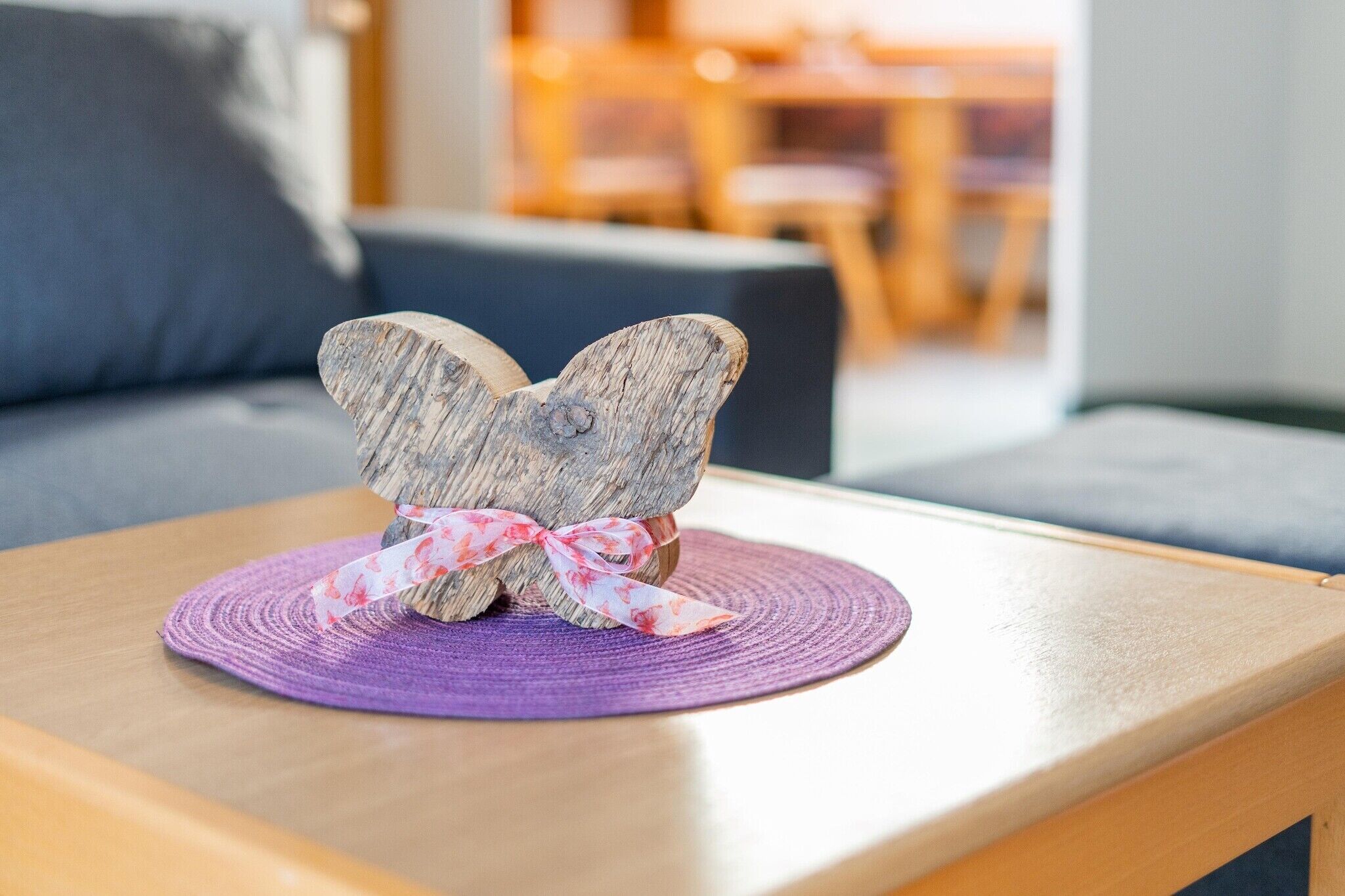 A wooden butterfly decoration on a wooden table with a purple placemat.