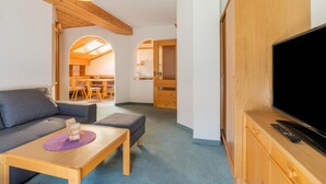 A modern living room with a sofa, ottoman, and coffee table, a flat-screen TV, and wooden furniture. - Chalet in Mittersill near Ski Slopes (Mittersill)