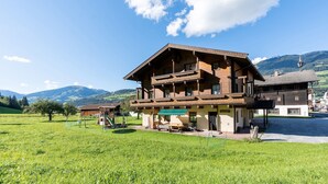 A wooden chalet with a balcony, situated in a green field with mountains in the background. - Chalet in Mittersill near Ski Slopes (Mittersill)