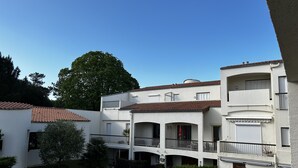 Ein mehrgeschossiges Wohngebäude mit Balkonen, einem Innenhof und einem Baum im Hintergrund.