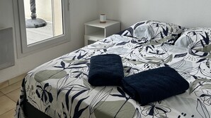 Ein Schlafzimmer mit Bett, Nachttisch, Fenster und integriertem Kleiderschrank.