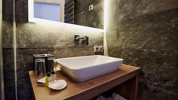 A modern bathroom with a rectangular sink, a wooden vanity, and a mirror.