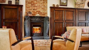 A cozy living room with a fireplace, leather armchairs, and a wooden cabinet. - Gut am See Hotel & Restaurant  (Görlitz)