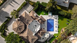 Vista aérea de un hotel con piscina en la azotea, varias terrazas y abundante vegetación.